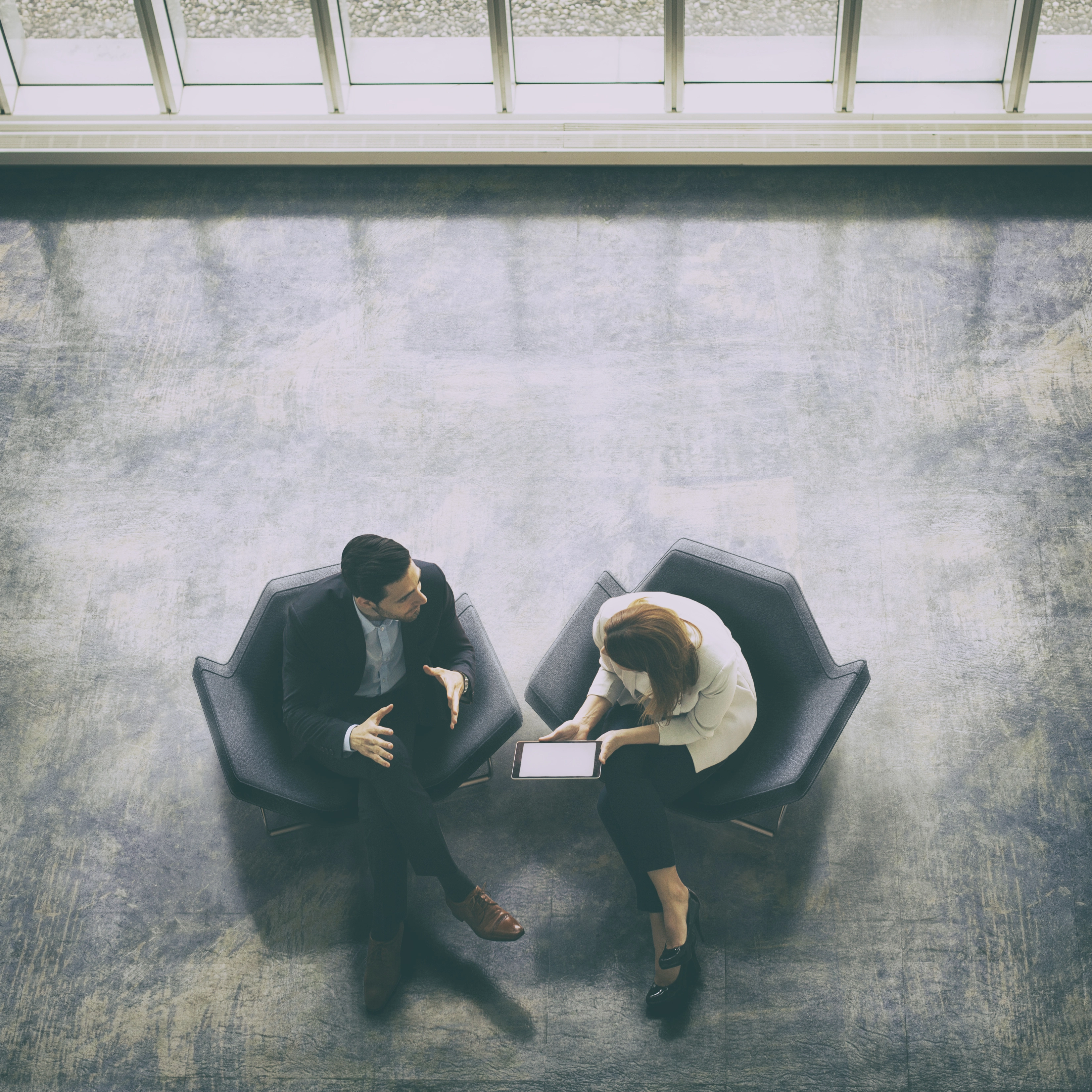 Man and woman discussing a new self-insurance and casualty insurance collateral funding program called Casualty insurance collateral funding while seated in two comfortable chairs
